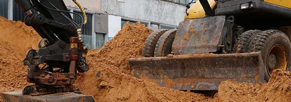 Excavator on dirt with clouds in sky